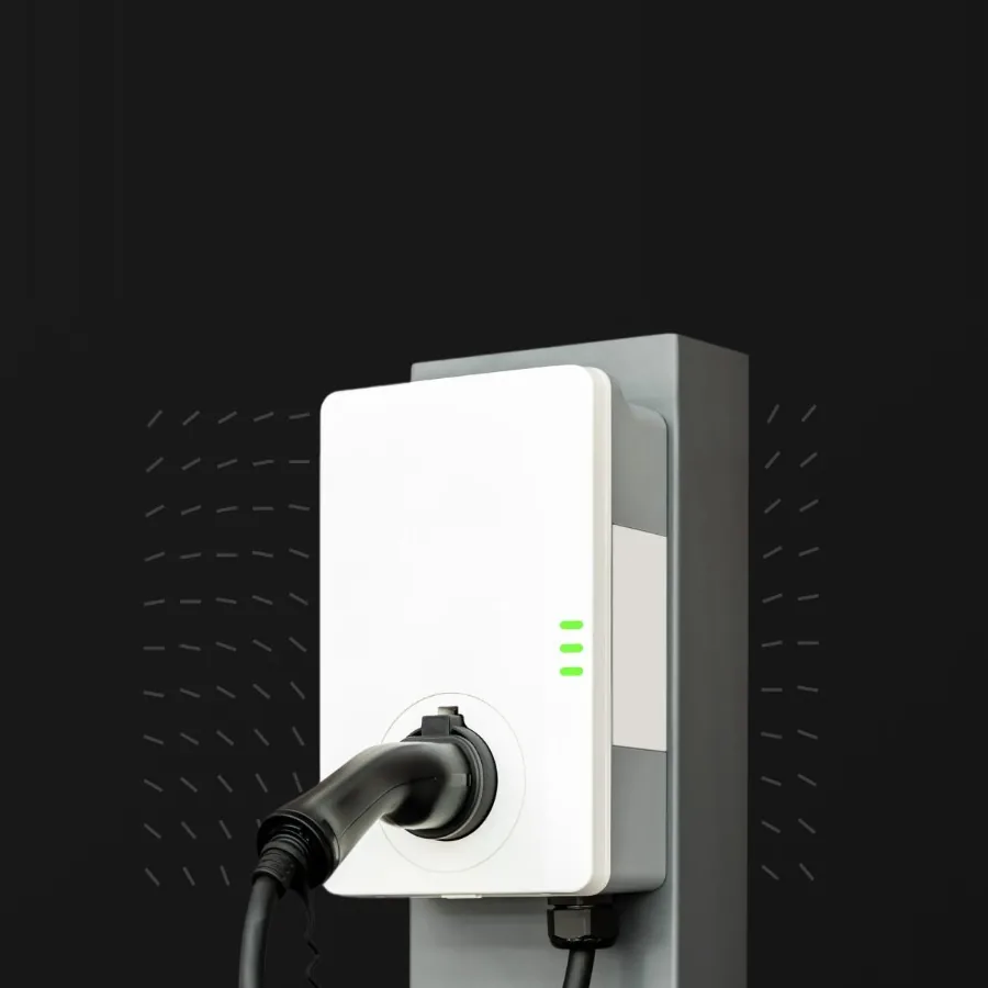 Wall-mounted DC charger: a compact white unit on a grey post, its charging cable attached