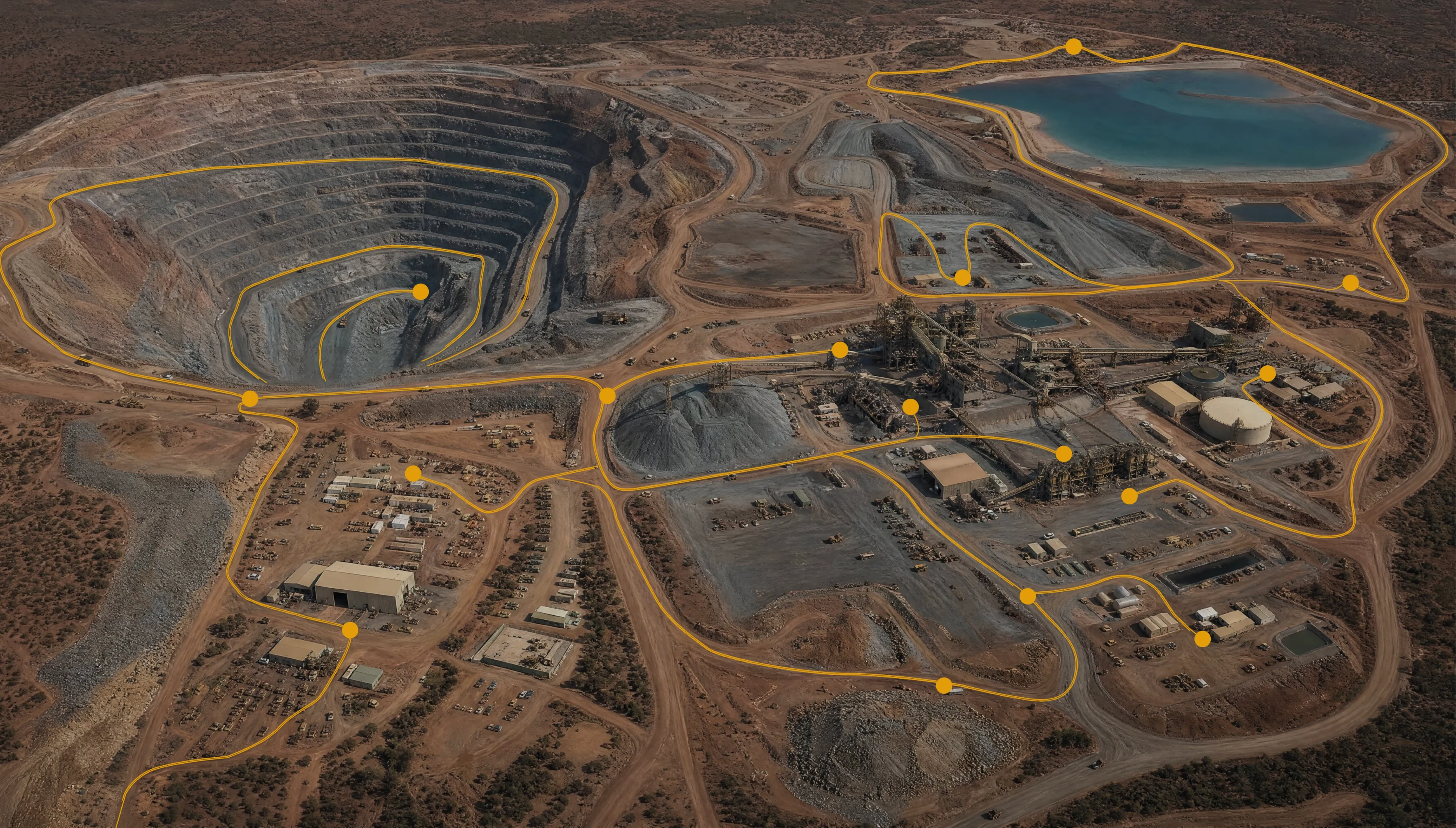 Aerial view of an open-pit mine site with its haul and service routes traced in gold