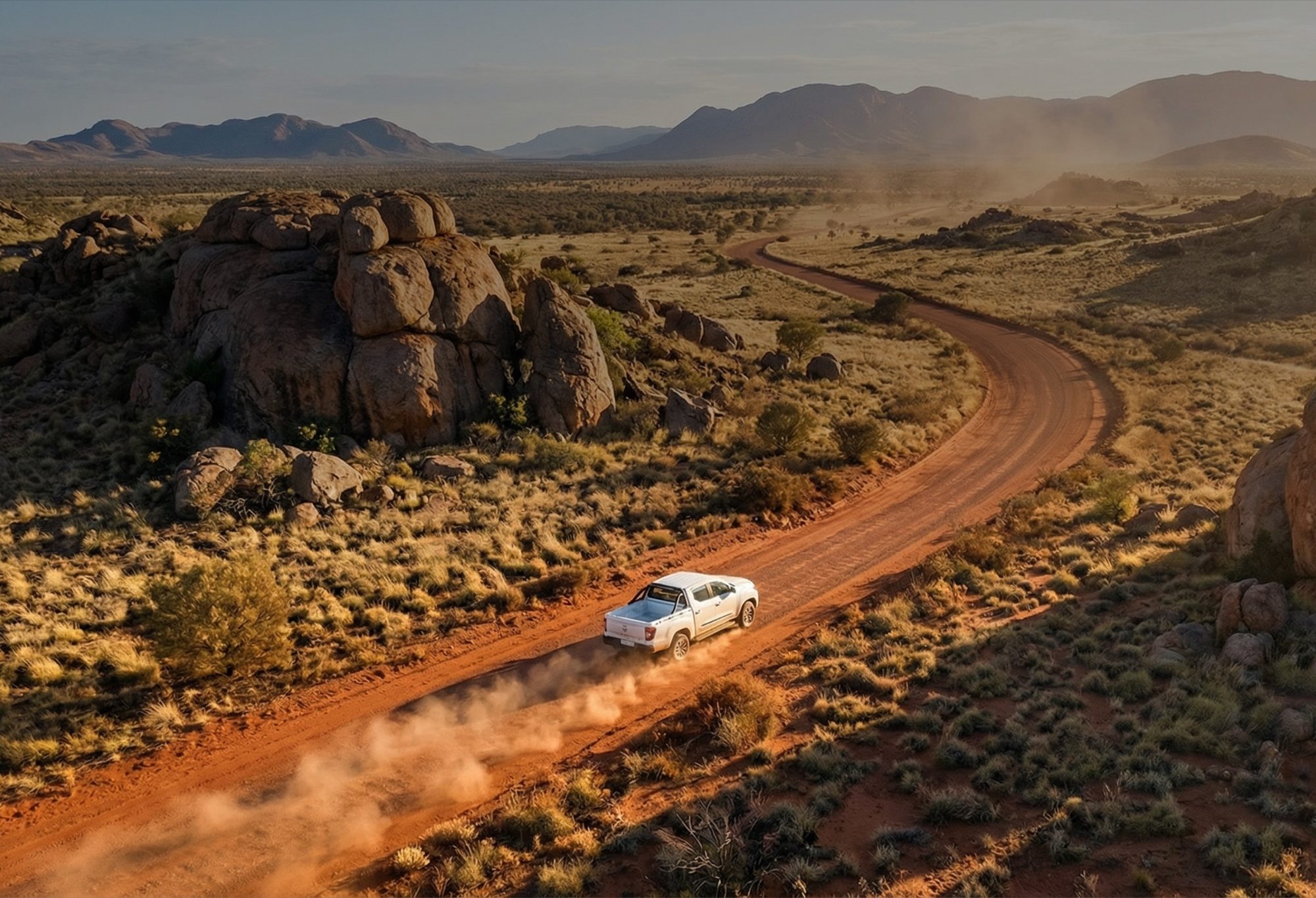 Tembo Tusker driving a red-dirt road through outback hills, dust trailing behind